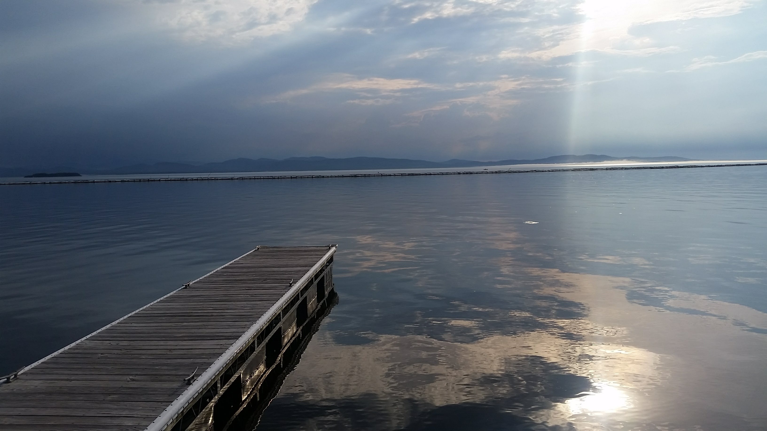 Vermont lake and wooden dock beneath dramatic autumn light