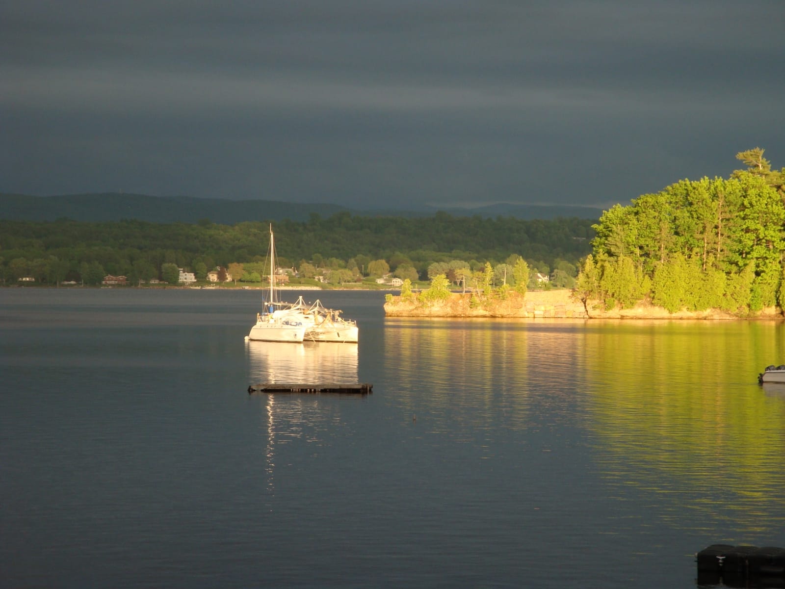 Sailboat on a Vermont lake beneath dramatic evening clouds
