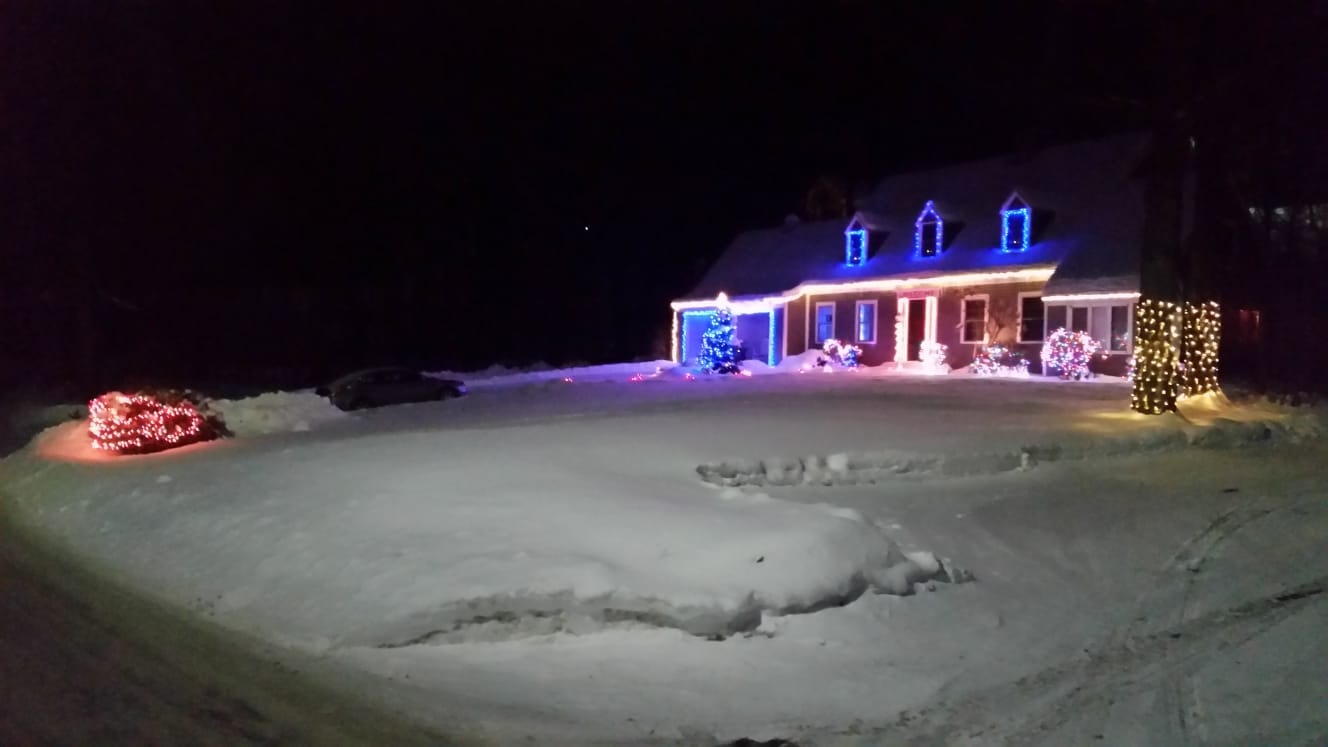 Wide view of a Vermont home decorated with Christmas lights in snow